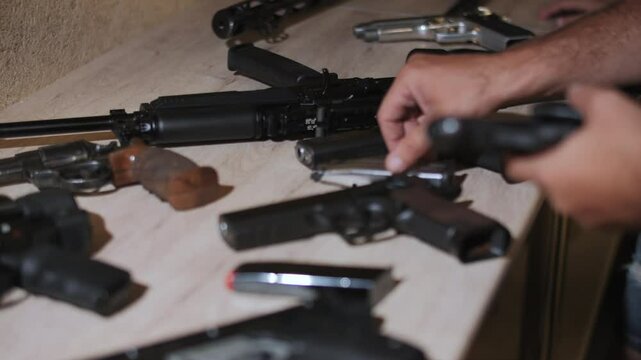 Man inspecting handguns on table