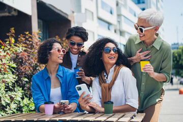 Photo of group friends women laugh drink coffee smart phone weekend chill street cafe table outdoors