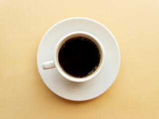 White cup with coffee on yellow background