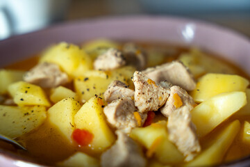 A bowl of soup with meat and potatoes. The meat is cut into small pieces and the potatoes are cooked. The soup is a mix of different flavors and textures, making it a hearty and satisfying meal