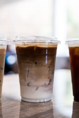 A plastic cup of iced coffee latte on wood table
