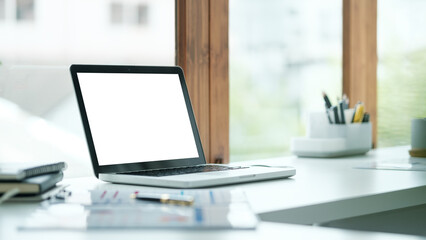 Modern workspace laptop with a white empty  screen on white desk,  for website mockups or digital presentations.