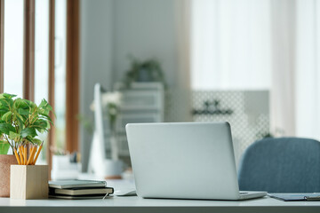 Serene and organized home office with laptop placed on a white desk.