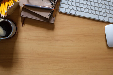 Top view of wooden desk with a cup of coffee, notebooks and a computer keyboard. Copy space for text.