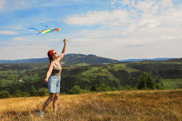 Fototapeta premium Smiling woman flying kite at field under blue sky. Space for text
