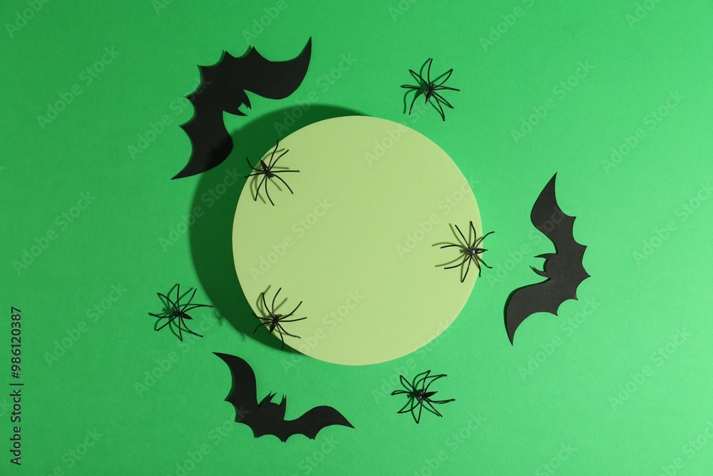 Wall mural Halloween celebration. Podium, decorative bats and spiders on green background, flat lay. Space for text