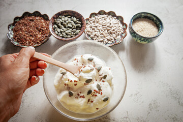 Seed cycling for hormonal balance - flax, pumpkin, sunflower and sesame seeds for different phases of menstrual cycle, women's health - a bowl of yogurt sprinkled with healthy seeds