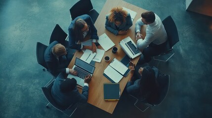 Above view of group of multi ethnic business people working in an office. Team of business people working on project in office, using laptop, writing notes at table with books, sharing learning tasks.