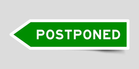 Green color arrow shape sticker label with word postponed on gray background