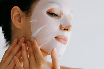 Beautiful young woman using white cosmetic nourishing wet mask