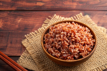 Cooked Thai Organic Red Jasmine Rice in wooden teak bowl.semi-milled rice.including fiber, B vitamins, and minerals such as iron and magnesium