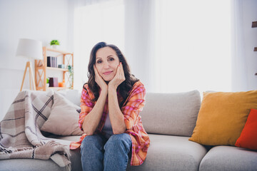 Obraz premium Photo of dreamy good mood woman dressed shirt arms cheeks sitting couch indoors house apartment room