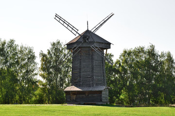 Old wooden windmill in a meadow on a sunny summer day.