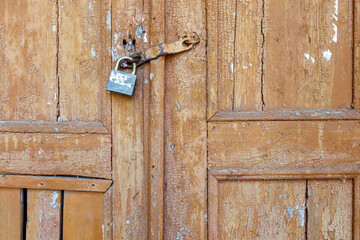 Old wooden door with rusty metal padlock close up