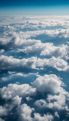 Aerial view of fluffy white clouds against a blue sky, with distant mountain silhouettes visible through the clouds. The scene captures a serene and tranquil atmosphere.