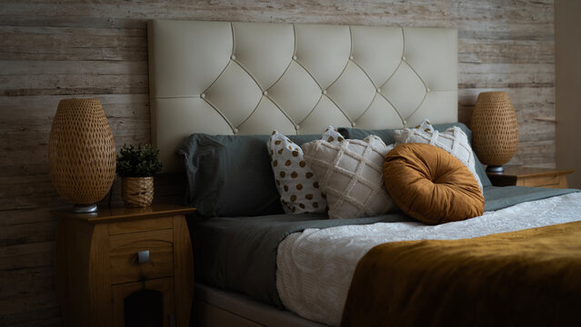 Dormitorio elegante con fondo de madera y cojines sobre la cama