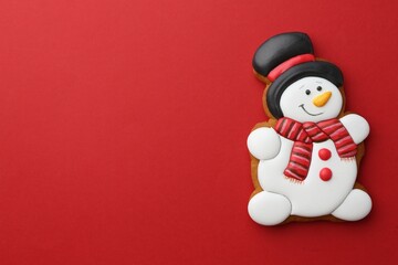 Tasty Christmas cookie in shape of snowman on red background, top view. Space for text