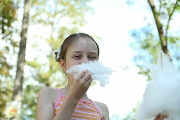 Portrait of little girl eating sweet cotton candy in park