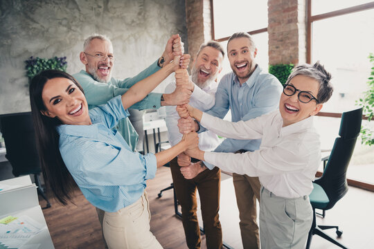 Photo of teamwork people working together hold hands suport teamwork comfortable modern office loft room interior indoors workspace