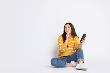 Young woman with smartphone on white background. Space for text