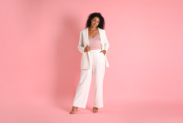 Beautiful woman in stylish suit on pink background