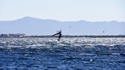 Man practising windfoil jumping in mediterranean sea.