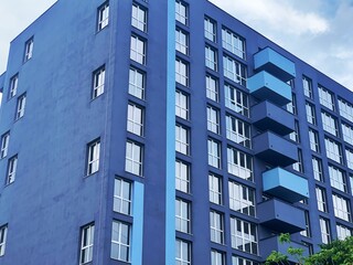 Real Estate concept. Minimal Architecture Background. Detail New blue high-rise Building or House Modern facade with windows. Contemporary geometrical architectural design backdrop. 