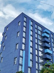 Fototapeta premium Real Estate concept. Minimal Architecture Background. Detail New blue high-rise Building or House Modern facade with windows. Contemporary geometrical architectural design backdrop. 
