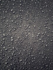 Water drops on black surface. Water droplets on dark background. Water droplets concept. Water drops on a black background. Banner with raindrops. Top view.