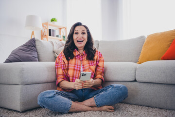 Photo of shiny excited woman dressed checkered shirt online shopping modern gadget indoors house apartment room
