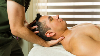 Man receiving a soothing head and neck massage from a male therapist on a massage table