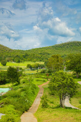 A serene mountain landscape with a winding path through green hills under a beautiful sky, showcasing the beauty of nature and countryside