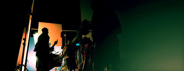 Silhouette of film crews and video camera on special dolly crane with film lights equipment and...