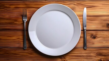 A white plate with a fork and knife rests on a wooden table, seen from above, ready for a simple meal.