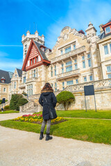 Obraz premium A woman visiting the Magdalena Palace next to the flowers in spring in the city of Santander