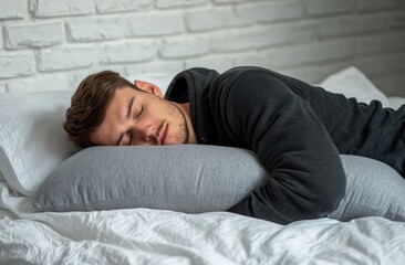A man is sleeping on his side with a stuffed animal and a pillow. He is wearing gray pajamas with a hood, against a white background. Advertising stock photo. Close-up of both hands holding a pillow