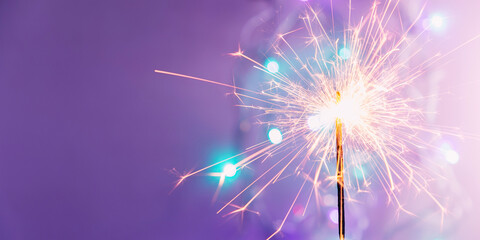 Obraz premium Beautiful glowing sparklers on colored background. Colorful sparklers sparkling against vibrant purple bokeh background creating festive and celebratory atmosphere. Christmas festive purple background
