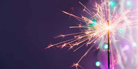 Beautiful glowing sparklers on colored dark background. Colorful sparklers sparkling against vibrant purple bokeh background creating festive and celebratory atmosphere. Christmas festive background