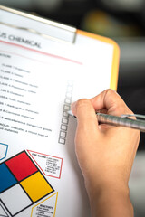 Action of a safety officer is marking on the chemical hazard material checklist to verify the type...