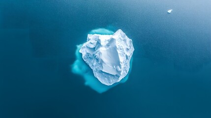 An aerial view of an iceberg floating in the water, showcasing its massive size and intricate details. The cold blue tones of the ice contrast with the dark ocean waters.