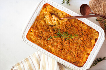 Traditional homemade macaroni and cheese casserole. Top down view table scene on a white marble. Holiday food concept.