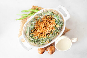 Traditional homemade green bean casserole. Above view table scene on a white marble background. Holiday food concept.