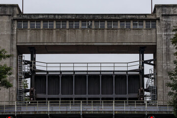Bridge with raised gate at entrance or exit of Bosscherveld lock, building and metal structure, river Meuse and Zuid-Willemsvaart canal, cloudy summer day in Maastricht, South Limburg, Netherlands