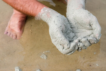 A man applies natural blue clay to his hands near the lake. Sandy beach. Use, meaning, and folk medicine.