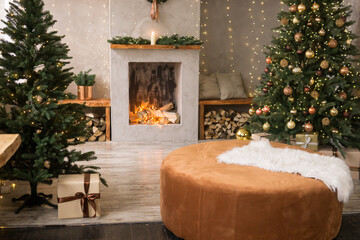 The interior of the Scandinavian-style living room, decorated for the Christmas holidays. Christmas tree next to the fireplace.