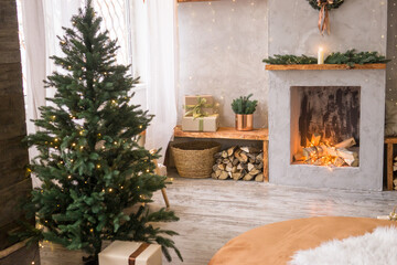 The interior of the Scandinavian-style living room, decorated for the Christmas holidays. Christmas tree next to the fireplace.