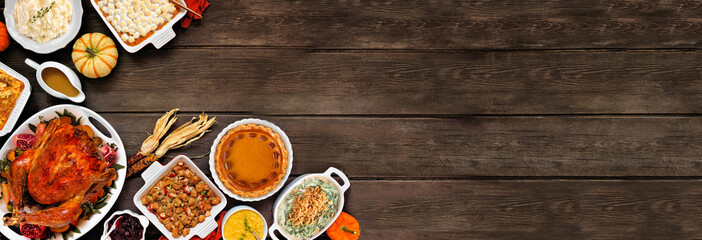 Traditional Thanksgiving turkey dinner. Above view corner border on a rustic dark wood banner background. Turkey, mashed potatoes, stuffing, casseroles, pumpkin pie and sides.