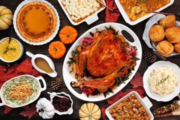 Traditional Thanksgiving turkey dinner. Top view table scene on a rustic dark wood background. Turkey, mashed potatoes, stuffing, casseroles, pumpkin pie and sides.