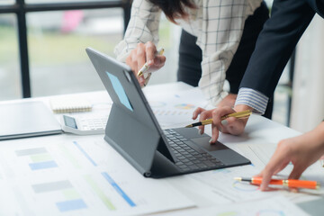 Business professionals meet in office, analyzing financial data on tablet. Diverse team plans future strategies, showcasing teamwork. Executives work together for company success