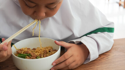 Happy cute asian using chopsticks eating chicken noodle